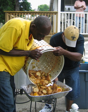 Two men dumping shrimp and corn from a food basket